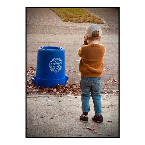 Little boy standing in front of an upside down recycling bin