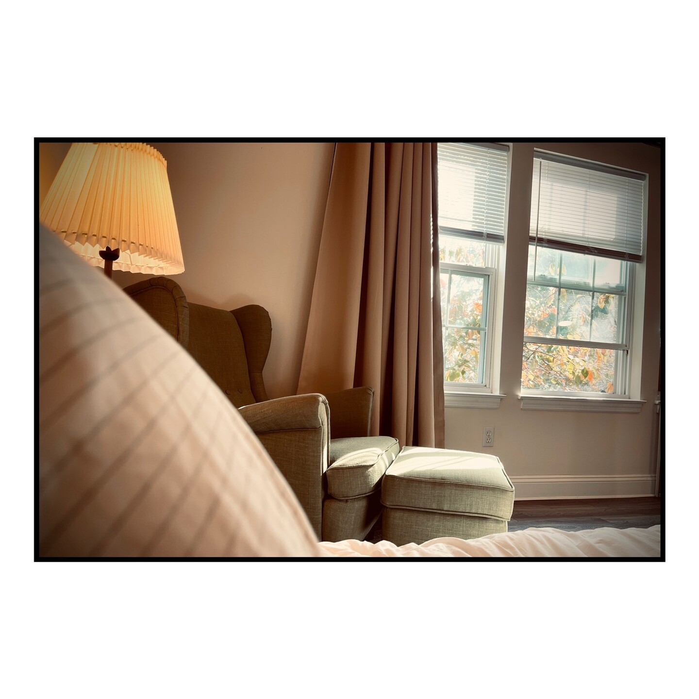 Scene of a chair and window from a bed.