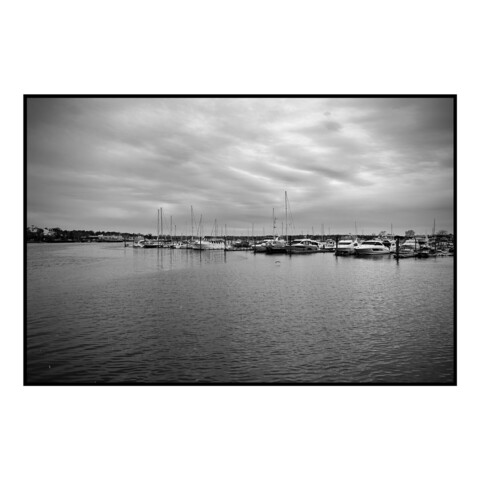 Landscape view of water with a marina in the background and overcast skies.