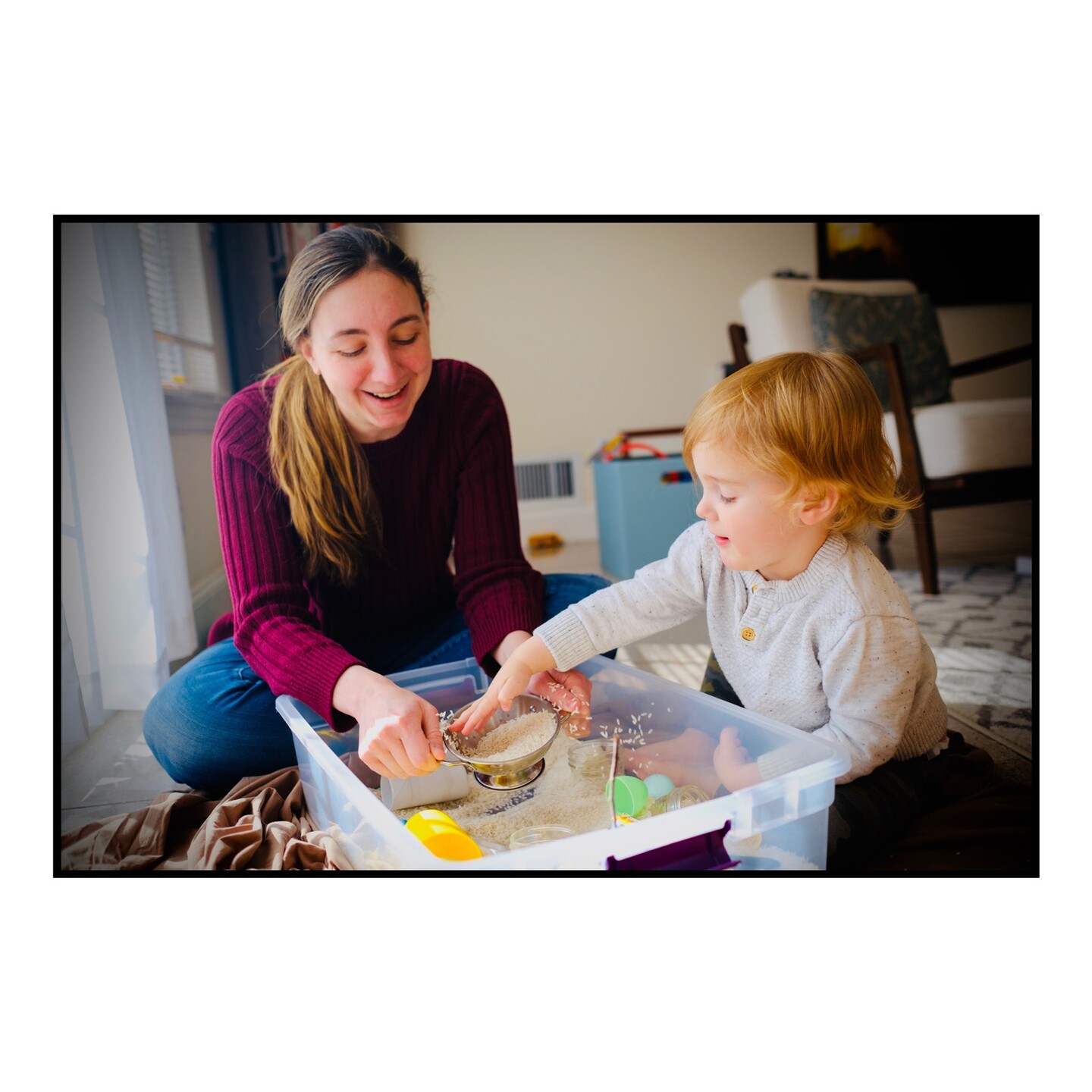 Mother and son playing with rice in a sensory bin.