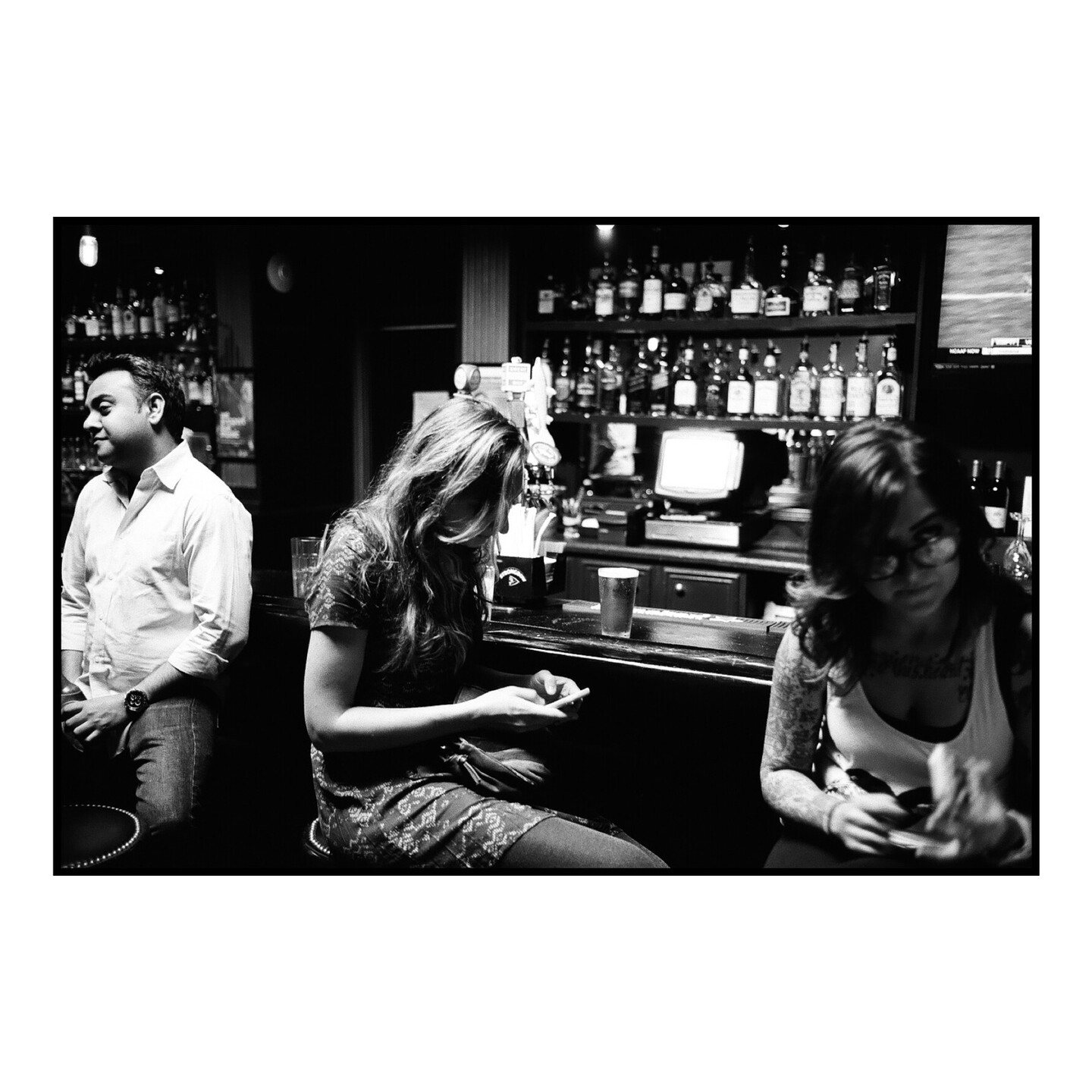 A woman checks her phone while sitting at a bar.