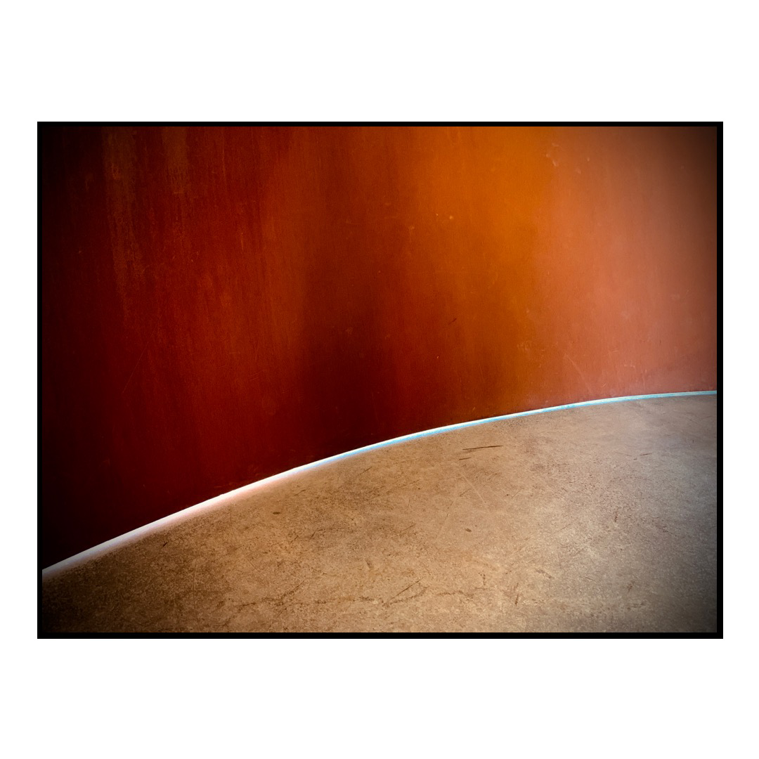 A sliver of light between the ground and a wall of metal 