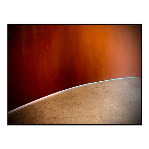 A sliver of light between the ground and a wall of metal 