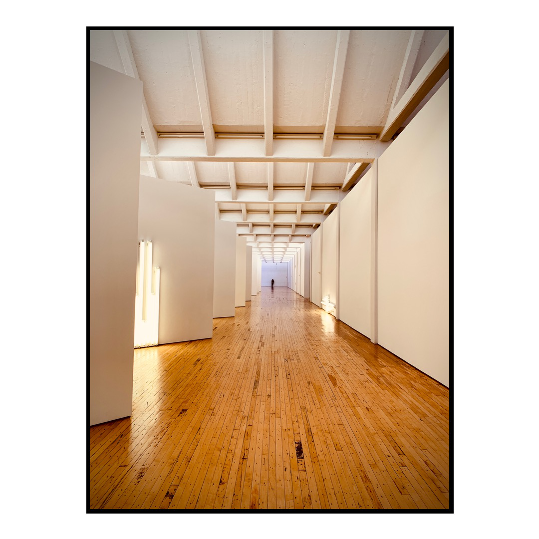 A hallway at Dia:Beacon with hardwood floors and white walls.