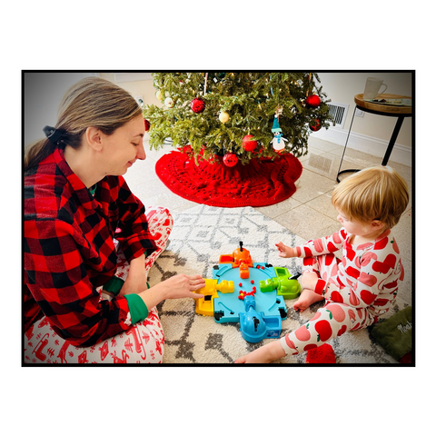 Mother and son on Christmas pajaplay hungry hippos by the Christmas tree.