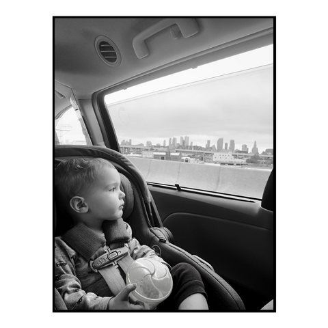 Our son in a car seat looking out the car window to the NYC skyline 