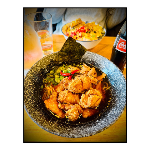 A table with a giant bowl of ramen and chicken 