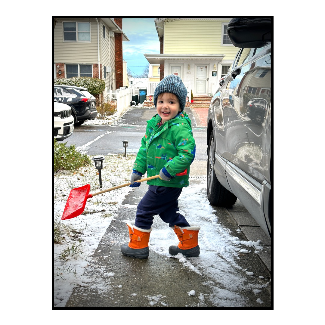 Our son shoveling a tiny amount of snow in the driveway.