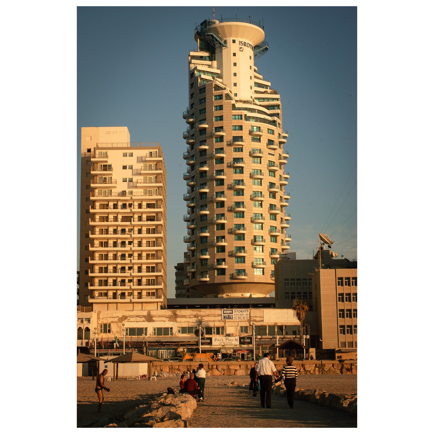 Sunset photo of tall hotel tower on the beach.