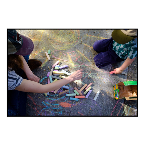 Mother and son playing with bright colored chalk on a sidewalk