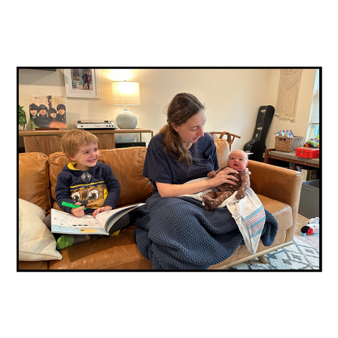 A woman on a couch with a 4 year old and a new baby.