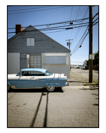 A classic car with blue and white trim in front of an old building 